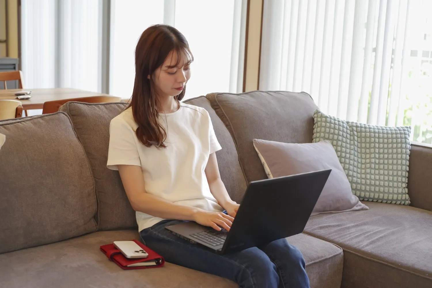 ソファでノートパソコンを開き、アーカイブを見返す女性
