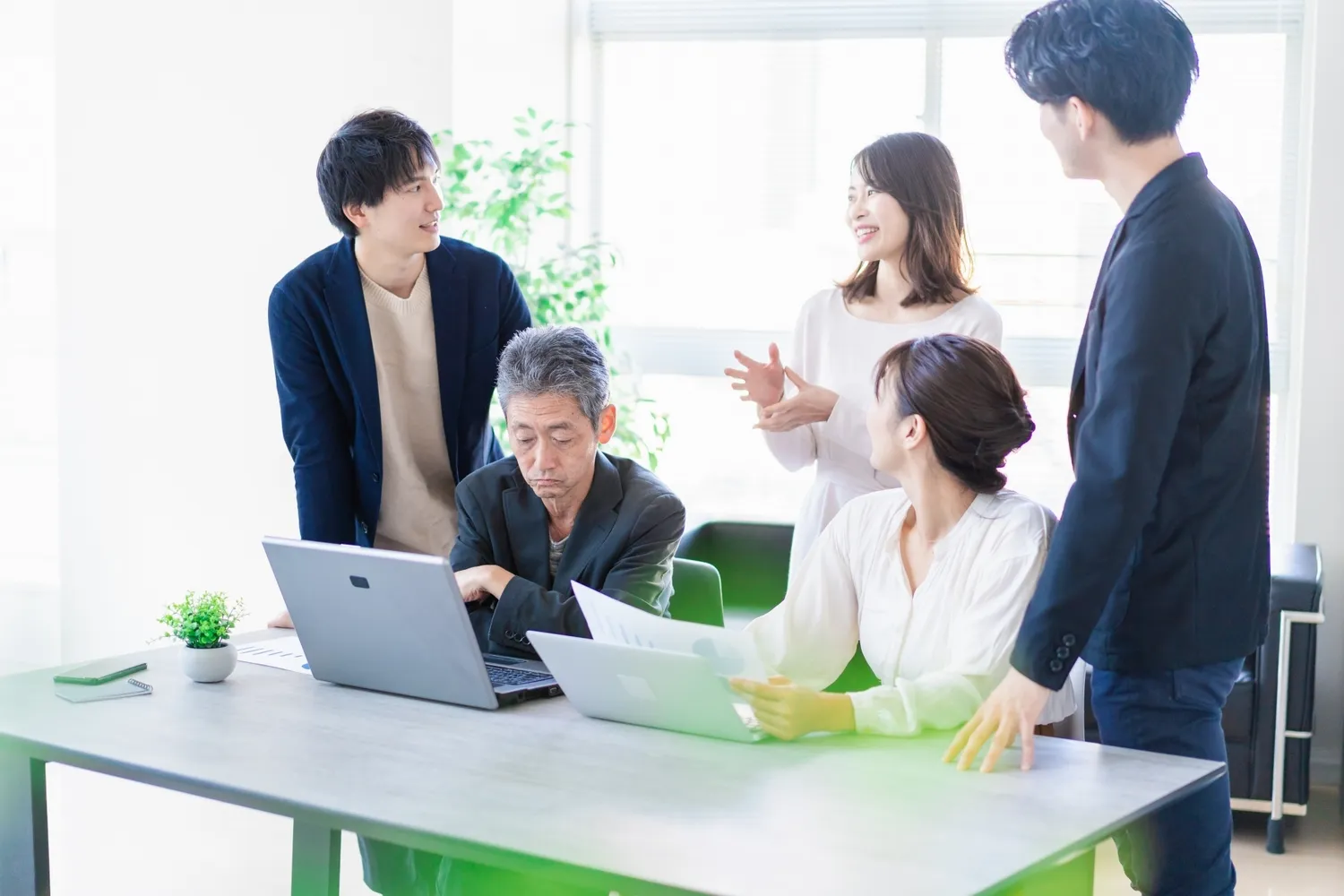 ノートパソコンを囲んで話し合うメンバー